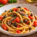 paghetti alla chitarra con alici, capperi, olive e pomodoro fresco. Un primo piatto saporito e semplice da preparare con pochi ingredienti.