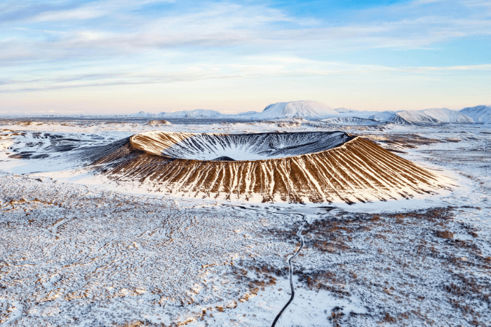 Cratere vulcanico circondato dalla neve nel paesaggio islandese, tra montagne e distese innevate.